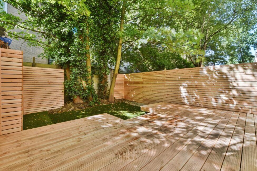 Професионална изработка на стилна дървена ограда с хоризонтално наредени една върху друга калибровани дъски и монтаж на декинг система