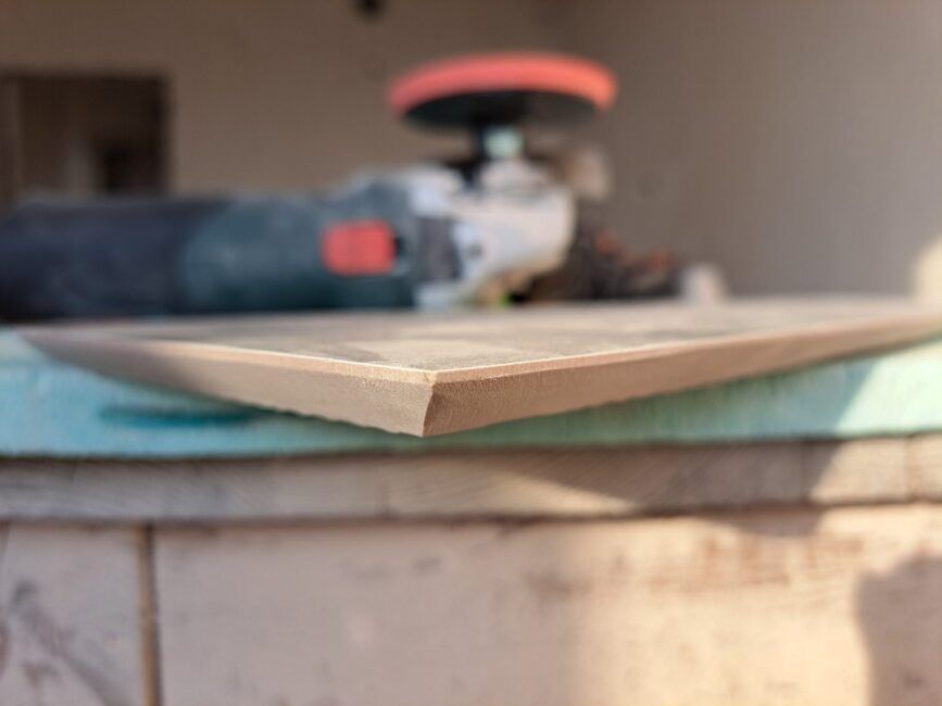 Герунг на плочки Етап от реновация на баня в Бургас - ъглошлайв върху маса с плочка, на която са загладени ръбовете след герунг