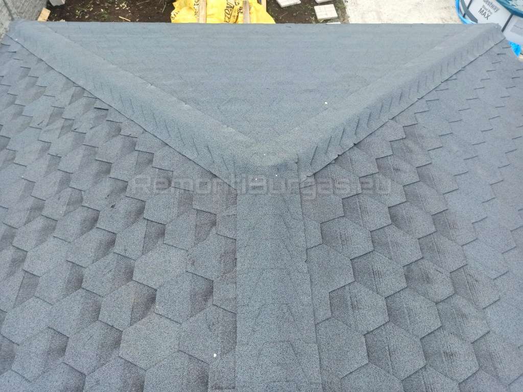 Покрив погледнат отгоре, при който се виждат прецизно монтирани шингли от битумни керемиди, които покриват билото на покрива